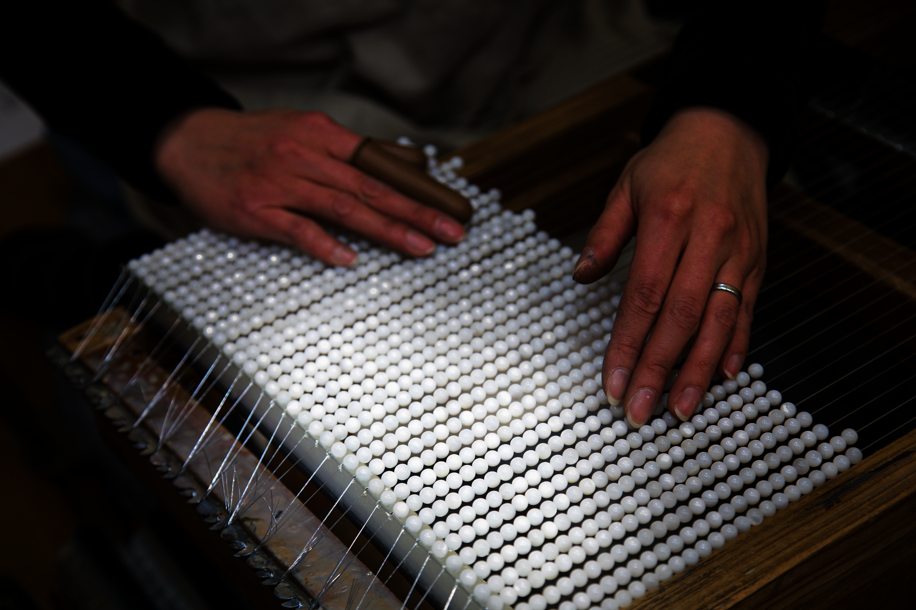 ガラスやプラスチック、どぶ貝などの原玉に真珠質の塗料をかぶせて作られます。一度にたくさん製造できるよう、原玉はまとめて針金に通されます。